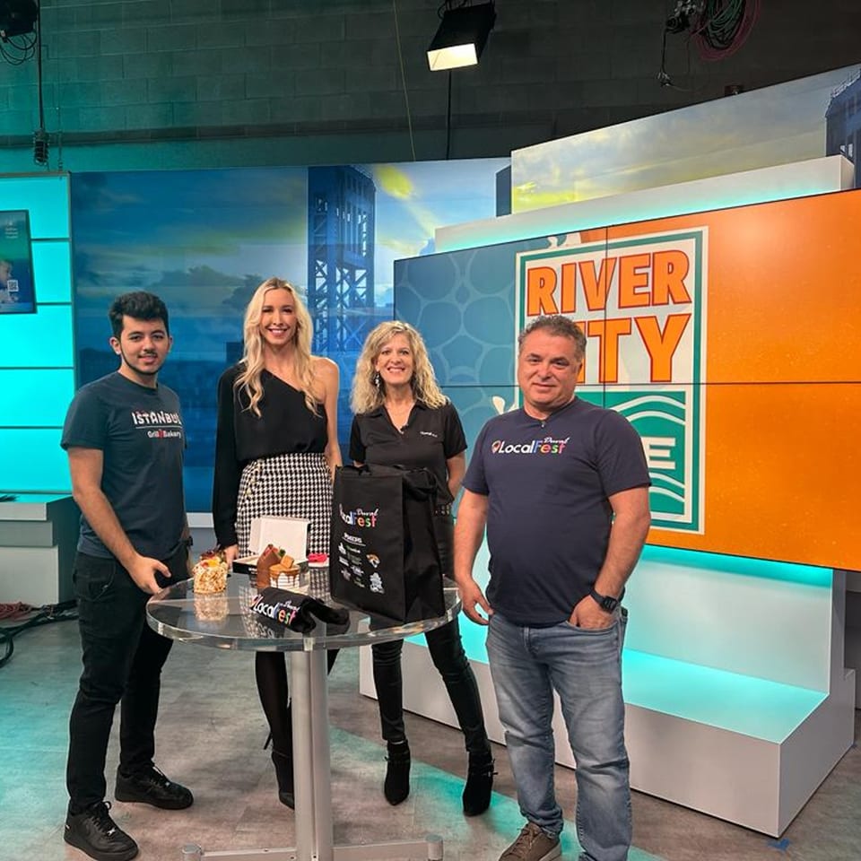 Four people, two men and two women, stand around a table with Turkish desserts on a TV set.