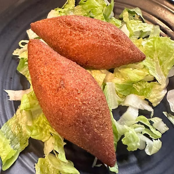 Two crispy Turkish kibbeh, or icli kofte, on a bed of fresh green lettuce.