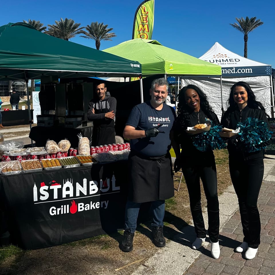 Four Istanbul Grill and Bakery staff members stand proudly behind a table laden with Turkish food.