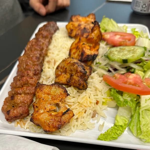 Turkish Adana kebab and chicken shish with rice and salad on a white plate.